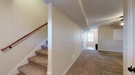 This two-story home in Clarksville, Tennessee offers a well-organized layout across two floors. The main level houses the kitchen, which features warm medium-toned wood cabinetry, tile flooring, and a full suite of black appliances including a range, microwave, dishwasher, and refrigerator. A pass-through window connects the kitchen to the adjacent living area, which is carpeted and brightened by a ceiling fan with light fixture. The lower level also includes bathroom access and additional storage.

Upstairs, carpeted stairs with a wooden handrail lead to a hallway that connects the bedrooms and bathrooms. The spacious primary bedroom offers generous square footage, two windows for natural light, a ceiling fan, and two closet doors. The second bedroom is also carpeted, features a ceiling fan, and receives ample natural light through a large window.

The three bathrooms include tile flooring in warm earth tones and functional fixtures throughout. One bathroom is accessible from the hallway and is conveniently positioned near both bedrooms, with warm wood vanity cabinetry visible from the corridor. Neutral wall colors and consistent finishes unify the home, creating a clean and functional living environment.