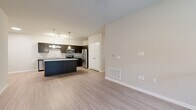 This single-floor, 3-bedroom, 2-bathroom residence offers a functional and modern layout designed for comfortable everyday living. The open-concept kitchen and living area serves as the heart of the home, featuring a large central island with granite countertops, dark espresso cabinetry, stainless steel appliances including a refrigerator, range, and microwave, and stylish pendant lighting that adds a contemporary touch. Light-toned luxury vinyl plank flooring flows seamlessly throughout the main living areas, complementing the neutral wall palette and creating a bright, cohesive aesthetic.

The living room is generously proportioned, offering ample space for entertaining or relaxing, and is fitted with a ceiling fan and a window that allows natural light to fill the room. The primary bedroom is a comfortable retreat, also featuring a ceiling fan for added convenience. The two additional bedrooms are carpeted and each equipped with double windows fitted with blinds, providing natural light and outdoor views.

The bathrooms are clean and functional, with one featuring a full tub-shower combination with chrome fixtures and wood-look tile flooring. Throughout the residence, the design emphasizes neutral tones, practical finishes, and a consistent modern sensibility that appeals to a wide range of lifestyles.