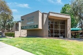 Located at 18014 Sherman Way in the Reseda neighborhood of Los Angeles, Unit #210 is a well-appointed single-floor residence that offers a cohesive and functional living environment. Rich, dark hardwood-style flooring runs throughout the entire unit, providing a warm and unified aesthetic from room to room.

The kitchen is thoughtfully designed with crisp white cabinetry, dark granite-style countertops, and a breakfast bar peninsula that connects to the main living area. White appliances, including a gas range and full-sized refrigerator, are neatly integrated alongside a stainless sink, making this a practical and efficient cooking space.

The open living area is spacious and filled with natural light courtesy of a large window that frames views of the surrounding greenery. A textured ceiling and neutral-toned walls create a clean, versatile backdrop, while a wall-mounted air conditioning unit ensures year-round comfort.

The bathroom features a matching granite-style countertop with an undermount sink and mirrored medicine cabinet above. A separate water closet houses the tub-shower combination, maintaining a clean division within the space.

Overall, the unit presents a consistent and tidy design language, with white trim, neutral walls, and warm flooring tones creating a comfortable and move-in-ready home in Los Angeles.