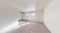 Located at 6401 N Warren Ave in Oklahoma City, Oklahoma, this single-floor home offers a practical and comfortable layout. The spacious living area is finished with neutral carpet and features a ceiling fan with light fixture, a textured ceiling, and a bank of windows that floods the room with natural light. The open sightlines from the entry door create an airy, welcoming atmosphere throughout the main living space.

The kitchen is well-appointed with rich, dark wood cabinetry featuring crown molding detail, light granite countertops, and a classic tile backsplash. A range with overhead ventilation hood, a double sink, and generous counter and storage space make this kitchen both functional and visually appealing. The kitchen flows seamlessly from the living area, separated by a half-wall with a pass-through counter, enhancing the open feel of the floor plan.

The bathroom is finished with large-format neutral tile surrounding a full soaking tub and shower combination, complemented by tile flooring and dark wood cabinetry above. The clean, cohesive tile work throughout the bathroom gives the space a polished and well-maintained appearance. Overall, this home presents a bright, functional layout suited for comfortable everyday living.