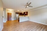 Located at 3129 Old Fairhaven Pkwy in Bellingham, WA, this well-appointed one-bedroom, one-bathroom unit offers a thoughtfully designed open-concept layout. Light-toned hardwood-style flooring flows throughout the entire space, creating a cohesive and clean aesthetic.

The combined kitchen and living area serves as the heart of the unit. The kitchen features rich dark-stained cabinetry, a full suite of stainless steel appliances including a refrigerator, range, and microwave, and a light-colored countertop peninsula with pendant lighting overhead — ideal for casual dining or entertaining. A ceiling fan enhances comfort in the living area, which is bathed in natural light from a sliding glass door leading to a private balcony with views of surrounding greenery.

The bedroom is a comfortable, well-lit retreat with a large window framing lush outdoor views and direct access to the balcony. Two closets provide ample storage, one featuring built-in wire shelving. The bathroom is clean and functional, offering a full soaking tub and shower combination with chrome fixtures. Neutral warm-beige walls throughout the unit contribute to a calm, inviting ambiance, while the efficient single-floor layout maximizes every square foot of living space.