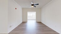Located at 8400 Veterans Pkwy in Columbus, GA, this single-story home offers five bedrooms and two full bathrooms across a well-organized floor plan. Light wood-style flooring runs throughout, complementing the crisp white walls and clean, modern aesthetic found in every room. The open-concept kitchen, dining, and living area serves as the heart of the home, featuring a large peninsula with a white quartz countertop, a matte black faucet, white shaker cabinetry, stainless steel appliances, and a skylight that brings in additional natural light. The dining area includes crown molding and a stylish multi-light chandelier. The living room benefits from natural light through side windows and is fitted with a ceiling fan. Each bedroom features the same light flooring and ceiling fans, with the primary bedroom offering a spacious closet with sliding panel doors. The bathrooms are finished in a modern style — one with a tiled tub-shower combo and matte black fixtures, and the other with a glass-door walk-in shower. A dedicated laundry room with wire shelving, washer/dryer hookups, and an electrical panel adds practical utility. The home presents a clean, move-in-ready interior with consistent finishes throughout.
