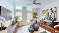 Located in Orlando's Baldwin Park neighborhood, this thoughtfully designed one-bedroom, one-bathroom home offers an efficient and well-appointed single-floor layout. Light hardwood flooring runs throughout, complementing the crisp white walls and creating a warm, cohesive aesthetic.

The open-concept kitchen is a standout feature, showcasing warm wood cabinetry paired with white upper cabinets, quartz countertops with a subtle veining pattern, a white subway tile backsplash, and stainless steel appliances including a full-size refrigerator and built-in microwave. A central island with seating provides an ideal space for casual dining or entertaining.

The living room benefits from elevated ceilings with transom windows that draw in generous natural light, a ceiling fan, and a glass door opening directly to the private patio. The bedroom is a serene retreat with large windows framing outdoor views, allowing abundant sunlight to fill the room. Two closets offer ample storage.

The bathroom features a floating wood vanity with a backlit mirror, a glass-enclosed walk-in shower, and clean, modern finishes throughout. A dedicated laundry area adds everyday convenience. This home presents a well-balanced blend of modern design and functional living in a prime Orlando location.
