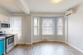 Located at 1538 Centre St in the heart of Detroit, MI, this efficiently laid-out single-floor unit offers a well-organized and functional living environment. The open-concept living and dining area is a standout feature, bathed in natural light streaming through a prominent bay window fitted with blinds. Light-toned luxury vinyl plank flooring runs throughout the main living spaces, complementing the soft gray walls and white trim for a clean, modern aesthetic. Exposed structural beams along the ceiling add an architectural detail to the space, while a wall-mounted mini-split unit ensures year-round climate comfort. The kitchen is thoughtfully appointed with white shaker-style cabinetry, warm butcher block-style countertops, stainless steel appliances including a refrigerator, range, and over-the-range microwave, as well as a dishwasher. A separate bedroom features plush carpeting, a wall-mounted climate unit, and a double window for additional natural light. The full bathroom includes a tub/shower combo with clean white surround. A dedicated utility room, closet, and entrance area round out the layout, providing practical storage and organizational functionality throughout the unit.