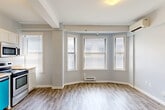 Located at 1538 Centre St in the heart of Detroit, MI, this efficiently laid-out single-floor unit offers a well-organized and functional living environment. The open-concept living and dining area is a standout feature, bathed in natural light streaming through a prominent bay window fitted with blinds. Light-toned luxury vinyl plank flooring runs throughout the main living spaces, complementing the soft gray walls and white trim for a clean, modern aesthetic. Exposed structural beams along the ceiling add an architectural detail to the space, while a wall-mounted mini-split unit ensures year-round climate comfort. The kitchen is thoughtfully appointed with white shaker-style cabinetry, warm butcher block-style countertops, stainless steel appliances including a refrigerator, range, and over-the-range microwave, as well as a dishwasher. A separate bedroom features plush carpeting, a wall-mounted climate unit, and a double window for additional natural light. The full bathroom includes a tub/shower combo with clean white surround. A dedicated utility room, closet, and entrance area round out the layout, providing practical storage and organizational functionality throughout the unit.