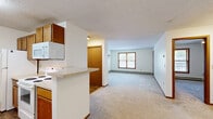 Located at 4605 W Chippewa Cir in Sioux Falls, SD, this one-bedroom, one-bathroom unit offers a practical and comfortable single-floor layout. The open-concept living area seamlessly connects the kitchen, dining, and living spaces, creating a bright and functional common area. The kitchen is outfitted with warm oak cabinetry offering generous storage, light-toned laminate countertops, a double-basin sink, and white appliances including a range, refrigerator, and microwave. Wood-look flooring runs throughout the kitchen, providing a durable and easy-to-maintain surface. The living area transitions to plush carpeting and features a wall-mounted air conditioning unit and baseboard heating, ensuring year-round comfort. Natural light filters in through windows trimmed in warm wood tones. The bedroom is a comfortable size, featuring carpet flooring, a ceiling fan with light fixture, a window with natural views, and baseboard heating. The bathroom includes a full tub-shower combination, wood-trimmed vanity, and wood-look flooring. A carpeted hallway connects the rooms and leads to four closets, providing exceptional storage throughout. Textured ceilings and warm wood trim are consistent throughout, lending the space a cohesive, classic character.