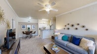 Located at 7613 Vestal Blvd in North Little Rock, Arkansas, this single-story residence offers a thoughtfully designed layout across two bedrooms and two full bathrooms. A welcoming entryway with tile flooring and crown molding transitions into a carpeted living room, where a ceiling fan with light fixture, decorative crown molding, and a large window fill the space with natural light. The open-concept design connects the living area to a dedicated dining space, creating a comfortable and functional gathering zone. The galley-style kitchen features white cabinetry, white appliances including a range, microwave, and refrigerator, light countertops, and wood-look flooring that extends into the adjacent laundry room, which accommodates a full-size washer and dryer. The primary bedroom is generously sized with plush carpet, a window for natural light, and a private en-suite bathroom. The second bedroom is equally comfortable with carpet flooring and convenient access to the second full bathroom. Both bathrooms include wood-look flooring, white vanities, and shower/tub combinations. A dedicated laundry room adds everyday convenience, rounding out a practical and inviting home.