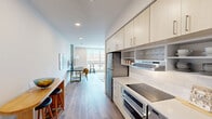 Located in Philadelphia's Spring Garden neighborhood, this contemporary 2-bedroom, 2-bathroom residence offers a thoughtfully designed single-floor layout. The open-concept living area is bright and inviting, anchored by large floor-to-ceiling windows that frame city views and flood the space with natural light. Wood-style plank flooring runs throughout, lending warmth and visual continuity.

The streamlined kitchen features light wood cabinetry with ample storage, white quartz countertops, a subway tile backsplash, stainless steel appliances including a refrigerator and range, and an integrated range hood — all arranged for functional efficiency. A breakfast bar provides additional seating and transitions naturally into the living and dining areas.

The primary bedroom is generously proportioned, featuring an exposed concrete structural column that adds an industrial touch, recessed lighting, a closet, and a large window with neighborhood views. The second bedroom also benefits from a sizable window, wall-mounted TV, and a comfortable layout. Both bathrooms are finished with large-format tile flooring and tub-shower combinations with rainfall showerheads, offering a clean, spa-inspired aesthetic. A connecting hallway ties all rooms together with ease, completing this well-appointed urban residence.