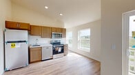 Located at 861 Kimball Ln in Verona, Wisconsin, this thoughtfully laid-out one-bedroom, one-bathroom unit offers a comfortable and functional living environment on a single floor. The open-concept kitchen anchors the living area, featuring warm wood cabinetry, light stone-look countertops, and a full suite of stainless steel appliances including a refrigerator, electric range, microwave, and dishwasher. Light hardwood-style flooring runs throughout the kitchen and main living area, lending a clean and modern aesthetic. The spacious bedroom is finished with soft carpeting and is equipped with a ceiling fan and multiple built-in closets, offering generous storage solutions. A sliding barn-style door adds a contemporary design touch to the bedroom entrance. Natural light filters in through a window with views of the surrounding green landscape. The bathroom includes a walk-in shower with modern brushed nickel fixtures and a separate storage or vanity area with additional hardwood-style flooring. Recessed lighting and ceiling fans contribute to the unit's bright and airy atmosphere throughout. The overall design is clean and neutral, creating a versatile canvas well-suited for a variety of living styles.