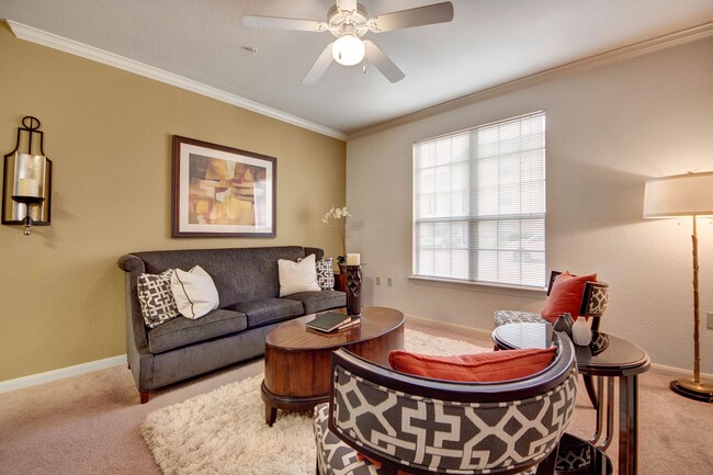 A cozy living room with a wide window overlooking the property and ceiling fan - The Residence at Heritage Park