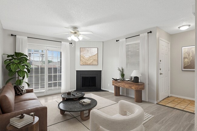 A renovated living room is shown with modern furniture, cozy fireplace, and view of private patio. - ReNew Holiday Hill®