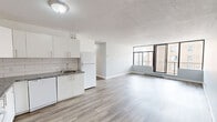 Located on the 11th floor at 810 Ouellette Avenue in downtown Windsor, this 2-bedroom, 1-bathroom unit offers a clean, modern aesthetic throughout. Light-toned vinyl plank flooring flows seamlessly across the entire space, complemented by soft grey walls and crisp white trim, creating a bright and cohesive feel.

The open-concept kitchen and living area forms the heart of the unit. The kitchen is well-appointed with white shaker-style cabinetry, granite-look countertops, a classic subway tile backsplash, and white appliances including a refrigerator and electric range. The adjacent living area is generously sized and benefits from large floor-to-ceiling windows and a sliding glass door that opens to a private balcony, offering expansive city views.

Both bedrooms are comfortably proportioned with large windows that bring in ample natural light and frame views of the surrounding Windsor cityscape. Baseboard heating is present throughout. The bathroom features a full soaker tub with a combination shower, framed by clean white subway tile from floor to ceiling. Additional practicalities include an in-unit laundry area and a dedicated closet for storage. The overall layout is functional and efficient, making excellent use of the available floor space.