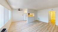 Located at 11509 216th St in Lakewood, California, Room 205 is a well-maintained single-floor unit that presents a bright and functional living space throughout. The open-concept living area features light wood-style flooring, neutral white walls, a textured ceiling, and a ceiling fan, creating an airy and comfortable environment. Large windows with vertical blinds allow natural light to fill the space, enhancing its clean and inviting atmosphere.

The kitchen is positioned adjacent to the living area, separated by a peninsula-style breakfast bar. It is equipped with white cabinetry featuring dark hardware, light countertops, a refrigerator, electric range, dishwasher, and a sink — providing ample storage and workspace. A secondary utility or storage area offers additional white upper and lower cabinetry with generous counter space along both walls and light wood flooring.

The bedrooms are carpeted and offer neutral tones, with windows providing natural light and textured ceilings overhead. Each room provides a comfortable and versatile space suitable for a variety of uses.

The bathroom is finished with light wood flooring, a single-sink vanity with white cabinetry, a large mirror, and a shower-tub combination enclosed by sliding frosted glass doors — offering a clean and practical design throughout.