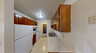 Located at 6400 Salisbury Rd in Maumee, Ohio, this single-floor, two-bedroom, one-bathroom residence offers a practical and well-organized layout. The galley-style kitchen is equipped with rich, warm-toned wood cabinetry, a double stainless steel sink, a full suite of white appliances including a refrigerator and electric range, and light tile flooring. Ample upper and lower cabinet storage provides excellent functionality. The kitchen opens toward the living area, creating an easy flow throughout the main space. The full bathroom features a tiled tub and shower combination, a vanity with storage, and classic mosaic tile flooring, offering a clean and straightforward design. Both bedrooms are carpeted and feature textured ceilings, baseboard heating units, and windows that allow natural light and exterior greenery views to filter in. Multiple closets throughout the unit provide generous storage options. A dedicated utility room adds further practicality to the layout. The overall ambiance is neutral and move-in ready, with a consistent color palette of soft whites and warm beige tones throughout, making the space feel bright and easy to personalize.