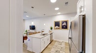Located at 1864 N Meridian St in Indianapolis, this one-bedroom, one-bathroom unit offers a thoughtfully designed single-floor layout with modern finishes throughout. The open-concept kitchen and living area serves as the heart of the unit, featuring white shaker cabinetry, a large island with seating for multiple bar stools, stainless steel appliances including a refrigerator, range, and microwave, and pendant lighting overhead. Light wood-tone flooring runs throughout, complementing the bright white walls and recessed lighting. The living area benefits from a full-length glass door that brings in natural light and adds a sense of openness. The bedroom is a comfortable retreat, complete with a ceiling fan, natural light from a window, and a spacious walk-in closet outfitted with wire shelving on multiple walls. The bathroom is clean and functional, featuring a glass-enclosed shower and wood-look tile flooring. A dedicated laundry area and additional closet storage add to the unit's practicality. The entrance provides a smooth transition into the living space, with the overall design maintaining a consistent, contemporary aesthetic that balances functionality with a clean, inviting ambiance.