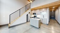 This 970 square foot property in Pendleton, SC, showcases a compelling blend of modern industrial and rustic design elements across two floors. The space is characterized by its open floor plan and unique architectural features. Polished concrete floors on the ground level provide a sleek, contemporary feel, while exposed wooden beams and a wooden ceiling add warmth and character.

The kitchen is a highlight, featuring light-colored cabinetry, stainless steel appliances, and a movable island, perfect for flexible meal preparation. A striking staircase with wooden treads and metal railings leads to the upper level, seamlessly integrating with the overall design aesthetic.

The bathrooms exhibit a luxurious touch with marble-effect tiling in the shower area and modern fixtures. One bathroom boasts a wooden floor, adding a cozy contrast to the otherwise contemporary space. The property also includes practical elements such as built-in storage and modern HVAC systems visible in some areas.

Throughout the home, neutral wall colors and ample lighting create a bright, airy atmosphere. The juxtaposition of industrial elements like metal ductwork with natural wood accents results in a harmonious and visually intriguing living space.