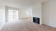 Located at 700 W Avenue I in Lancaster, CA, this one-bedroom, two-bathroom unit offers a thoughtfully laid-out single-floor plan. The bright and open living room is a standout feature, showcasing a wood-burning fireplace, soft wall-to-wall carpeting, a textured ceiling, and a ceiling fan. A sliding glass door leads to a private balcony with views of the surrounding neighborhood and mature trees. Natural light fills the space through multiple windows. The galley-style kitchen is efficiently designed with white cabinetry, dark granite-look countertops, a gas range, refrigerator, and hardwood-style flooring — maximizing functionality in a compact footprint. The spacious primary bedroom features plush carpeting, a large window with neighborhood views, and dual mirrored sliding closet doors offering generous storage. Both bathrooms are finished with hardwood-style flooring, white cabinetry, dark countertops, and tub/shower combinations with high windows for natural light and privacy. A connecting hallway links the living areas to the bedrooms and bathrooms. The exterior of the building features stucco siding with a classic red tile roof, consistent with the surrounding community's architectural style.