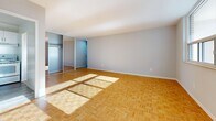 This well-appointed 2-bedroom, 1-bathroom unit is laid out on a single floor, offering a functional and comfortable living environment. Distinctive parquet wood flooring runs consistently throughout the space, adding warmth and character to every room.

The spacious living room is a standout feature, anchored by a large picture window that frames urban skyline views and fills the room with abundant natural light. The kitchen, accessible directly from the living area, is equipped with white shaker-style cabinetry — both upper and lower — and features granite countertops with a classic stainless steel sink, providing generous prep and storage space.

The primary bedroom is generously sized, benefiting from natural light through its own dedicated window with city views. It includes a built-in closet with mirrored sliding doors, adding both storage and a sense of depth to the room. The second bedroom is similarly bright, with a corner window and the same warm parquet flooring.

The bathroom is finished in a clean, all-white palette, featuring small mosaic floor tiles, a combined tub and shower, and a vanity with under-sink storage. Two hallways and an additional closet provide practical storage solutions throughout. The layout flows efficiently, connecting all rooms through well-organized corridors.
