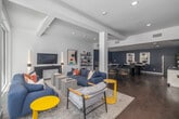 Located at 417 Centinela Ave in Inglewood, California, this thoughtfully designed single-floor space offers a seamless blend of comfort and functionality across a living room and office area. Rich hardwood flooring runs throughout, anchoring the contemporary aesthetic and providing a warm contrast to the crisp white walls and deep navy blue accents found in the office zone.

The living room is bathed in natural light, courtesy of expansive floor-to-ceiling glass walls and sliding doors that open directly to an outdoor courtyard, creating an effortless indoor-outdoor connection. Recessed lighting and structural columns add architectural character, while the open layout encourages a relaxed yet purposeful flow between zones.

The office area features deep navy walls that lend a focused, creative atmosphere. A marble-topped communal table serves as a central gathering point, complemented by a kitchenette with white cabinetry, a stainless steel refrigerator, and a wall-mounted living plant display. A dedicated lounge nook with built-in bench seating, patterned acoustic wall panels, and white-topped tables provides additional workspace or meeting space.

Throughout, curated artwork, open metal shelving, and bold yellow accent pieces add personality and visual interest, making this a dynamic and inviting environment suited for both collaboration and relaxation.
