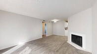 Located at 1770 W Prince Rd in Tucson, Arizona, this two-bedroom, one-bathroom residence offers a practical and well-appointed single-floor layout. The open living room serves as the heart of the home, featuring wood-look flooring, a textured ceiling, a white-surround fireplace, and a pendant light fixture. A sliding glass door floods the space with natural light and provides direct outdoor access. The kitchen is well-equipped with crisp white cabinetry, gray subway tile backsplash, white countertops, a stainless steel double sink, and stainless steel appliances including a refrigerator and dishwasher. Both bedrooms are comfortably sized, each featuring wood-look flooring, a textured ceiling, natural light from windows with blinds, and a dedicated closet with built-in shelving. Wall sconces in the bedrooms add a warm lighting touch. The full bathroom includes a single-sink vanity with a framed mirror, a tub-shower combination, and wood-look flooring with brushed nickel fixtures throughout. A hallway connects the bedrooms and bathroom. The overall aesthetic is clean and neutral, with light gray tones and modern finishes creating a cohesive, move-in-ready feel.