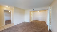 This single-floor residence offers a straightforward, functional layout with warm neutral tones and consistent design elements throughout. The living area is generously sized, featuring plush brown carpeting and a large picture window that allows natural light to fill the space while offering views of surrounding greenery. A tiled entryway transitions smoothly into the carpeted living zone, which connects openly to a designated dining area equipped with a ceiling fan and light fixture.

The galley-style kitchen is efficiently designed with white cabinetry lining both sides, white appliances including an electric range and a stainless steel refrigerator, a built-in dishwasher, a double sink, and light tile flooring beneath overhead fluorescent lighting.

The bedrooms are carpeted and each equipped with ceiling fans. One bedroom features a walk-in closet with built-in shelving and railing, while another includes direct access to a bathroom. The bathroom includes a white vanity with an integrated sink, louvered mirror cabinet, and a tiled shower-tub combination. Textured ceilings and white trim are consistent throughout, contributing to the unit's clean, cohesive aesthetic.