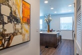 This single-story residence presents a cohesive modern design across all of its living spaces. The open-concept kitchen serves as a functional centerpiece, outfitted with rich dark-wood cabinetry extending to the ceiling, light quartz countertops, stainless steel appliances including a refrigerator, range, microwave, and dishwasher, and a peninsula with bar seating. Wood-look flooring runs throughout the kitchen and connects visually to the entry corridor, where recessed lighting and a louvered utility closet door add practical detail.

The living room features notably elevated ceilings that enhance the sense of openness, with large windows fitted with horizontal blinds allowing generous natural light while maintaining privacy. A second seating area adjacent to the living room offers additional flexible space with its own window views.

The bedrooms are carpeted for comfort, each with ample natural light from individual windows. One bedroom includes a ceiling fan, while another features tasteful wall art and coordinating nightstands. The primary bathroom is generously proportioned, offering dual sinks with dark cabinetry, quartz counters, wood-look flooring, and a separate shower-tub combination behind a private door. The overall aesthetic throughout is clean, neutral, and consistently modern.