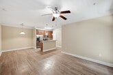 This well-appointed 2-bedroom, 3-bathroom residence offers 1,010 square feet of thoughtfully designed single-floor living space. The open-concept kitchen and living area serves as the heart of the home, showcasing warm wood cabinetry, granite countertops, stainless steel appliances — including a refrigerator, microwave, and range — and a peninsula island with pendant lighting and a built-in sink, ideal for casual dining or food preparation. Crown molding adds a refined architectural touch throughout the main living areas. Hardwood-style flooring flows consistently across the entire unit, lending a cohesive and clean aesthetic. The primary bedroom measures 170 square feet and features crown molding, a ceiling fan, multiple windows with outdoor views, and direct access to the private balcony, which overlooks a serene, tree-lined landscape. The second bedroom also includes a ceiling fan and natural light from large windows. Each of the three bathrooms is finished with granite-topped vanities and wood cabinetry. Two bathrooms include a tub/shower combination. Additional spaces include a dedicated laundry room equipped with a washer and wire shelving, a hallway, and two closets for ample storage throughout.