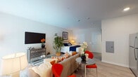 Located at 74 W Washington St in Oswego, Illinois, this single-floor studio unit offers a thoughtfully designed open-concept layout that seamlessly combines the living, sleeping, and dining areas into one cohesive space. Light wood-style flooring runs throughout, contributing to a clean, modern aesthetic.

The living area is bright and welcoming, featuring a large sliding glass door with vertical blinds that allows natural light to fill the space. The open floor plan provides flexibility in furnishing arrangements, accommodating both a comfortable seating area and a dedicated sleeping space within the same room.

The kitchen is a standout feature, equipped with rich, dark espresso-toned cabinetry that extends to the ceiling for ample storage. Light granite countertops provide a striking contrast, while a full suite of stainless steel appliances — including a gas range, built-in microwave, dishwasher, and refrigerator — adds a modern, functional touch. A double-basin sink completes the well-appointed kitchen.

The bathroom is clean and simply finished, with light flooring that complements the rest of the unit. The overall design of the space emphasizes practicality and contemporary style, making efficient use of its single-floor footprint.