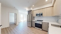 Located at 988 S Manhattan Pl in Los Angeles, CA, this thoughtfully designed one-bedroom, one-bathroom unit offers a clean, contemporary aesthetic throughout. Light wood-tone luxury vinyl flooring flows seamlessly across the open floor plan, connecting the kitchen, living area, and bedroom with a cohesive, modern feel.

The kitchen is a standout feature, equipped with a full suite of stainless steel appliances including a gas range, over-the-range microwave, refrigerator, and dishwasher. Light wood cabinetry extends from floor to ceiling, providing ample storage, while crisp white countertops and a neutral tile backsplash complete the polished look.

The living area is bright and open, with natural light filtering in through windows that offer views toward the private balcony — an ideal spot for outdoor relaxation. The bedroom is a comfortable, well-proportioned retreat with clean white walls and direct access to a spacious walk-in closet featuring built-in shelving and dual hanging rods. A second closet provides additional storage convenience.

The bathroom is finished with large-format marble-look tile flooring, a soaking tub with shower, and a wood-accented vanity. In-unit laundry adds everyday practicality to this well-appointed Los Angeles residence.