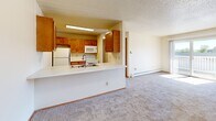 Located at 6010 Creston Ave in Des Moines, Iowa, this two-bedroom, one-bathroom unit offers a practical and comfortable single-floor layout. The open kitchen features warm wood-toned cabinetry, white appliances including a refrigerator, range, dishwasher, and microwave, along with wood-look vinyl flooring and a pass-through counter that connects to the carpeted living area, creating an open and airy feel. Natural light flows into the living space through a large window, complemented by a baseboard heating system. The primary bedroom is a well-sized retreat with a ceiling fan, a window with exterior views, and plush carpeting. It connects to a dedicated walk-in closet outfitted with dual hanging rods and a built-in shelving unit, offering generous storage. The second bedroom also features carpeted floors, a large window, and a sliding door closet. The full bathroom includes a wood-toned vanity, mirrored medicine cabinet, a shower-tub combination, and wood-look vinyl flooring. Textured ceilings are present throughout the unit, adding a consistent design element. Baseboard heaters are found in multiple rooms, ensuring efficient climate control throughout the space.