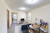 Located at 900 Wigwam Hollow Rd in Macomb, Illinois, this single-floor, one-bedroom, one-bathroom unit offers a practical and well-organized layout designed to maximize every square foot. The living room serves as the central gathering space, featuring neutral carpet flooring, warm cream-toned walls, and a window fitted with horizontal blinds that allow natural light to filter in while providing privacy. The room comfortably accommodates both a seating area and a dining space, making it functional for everyday living. Adjacent to the living room, the bedroom is a well-proportioned private retreat with its own window offering natural light, soft carpet underfoot, and a closet with sliding wood-trimmed doors for convenient storage. The kitchen is equipped with wood-toned cabinetry and a window that brings in additional daylight, keeping the space bright and practical. The combined bathroom and laundry room is a standout feature, efficiently integrating both functions into a single space, complete with warm wood-finish cabinetry, a sink, and a shower. A separate utility area near the entrance provides additional cabinet storage and a secondary sink. Throughout the unit, consistent warm wood door and window trim, light-colored walls, and carpeted floors create a cohesive, understated aesthetic.