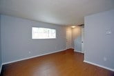 Located at 827 41st Street in Newport News, Virginia, this two-story home offers a practical and well-maintained living environment with consistent finishes across both floors. The main level features a spacious living area with light-toned hardwood flooring, textured gray walls, and a wide window that draws in natural light while offering neighborhood views. A staircase leads to the upper level, maintaining an open and accessible layout. The kitchen is a standout space, outfitted with rich dark espresso cabinetry, granite-style countertops, and a full suite of black appliances including a refrigerator, range, dishwasher, and over-range microwave. Light speckled flooring completes the kitchen's functional design, and an electrical panel is conveniently accessible nearby. A full bathroom on the lower level includes a tub-shower combination with white tile surround, a vanity, and a window for ventilation. The upper level hosts additional rooms with warm hardwood flooring, textured walls in soft gray tones, and windows that allow natural light to filter in. A second bathroom provides louvered door storage access and tile flooring. Throughout the home, clean white trim and neutral tones create a cohesive, move-in ready atmosphere.