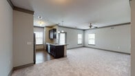 This single-floor residence offers a thoughtfully designed open-concept layout that seamlessly connects the kitchen and living areas. A carpeted hallway leads from the entry into the main living space, where multiple windows dressed with blinds allow abundant natural light to fill the room. A ceiling fan overhead adds comfort to the generously sized living area.

The kitchen serves as the heart of the home, featuring dark espresso cabinetry, granite countertops, a tile backsplash, and a full suite of stainless steel appliances including a refrigerator, electric range, and built-in microwave. A peninsula with pendant lighting provides additional prep space and a casual dining option, while hardwood-style flooring grounds the kitchen zone.

The bedrooms are carpeted and well-sized, each featuring ceiling fans and windows with outdoor views. Walk-in closets equipped with wire shelving systems offer generous storage capacity. An additional utility-style closet with wire shelving and electrical access provides further storage flexibility.

The bathrooms are finished with warm hardwood-style flooring, dark vanities with granite countertops, and a framed glass walk-in shower accented with classic white subway tile and grey accent tile. A grab bar is also present, adding a practical accessibility feature. Crown molding throughout the space adds a refined finishing touch to the overall design.