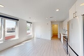 Located at 42 N Beacon Street in Boston's Allston neighborhood, this thoughtfully designed one-bedroom, one-bathroom unit offers a clean, modern aesthetic throughout. Light wood-toned flooring flows continuously across the entire space, complementing the crisp white walls and recessed lighting that create a bright, airy atmosphere.

The entrance hall leads into an open-concept living area bathed in natural light from large windows fitted with roller shades. The galley-style kitchen is well-appointed with high-gloss white cabinetry, quartz countertops, a white subway tile backsplash, stainless steel appliances including a range, microwave, refrigerator, and dishwasher, and a single-basin sink with a modern pull-down faucet. A wall-mounted mini-split unit provides efficient climate control.

The bedroom features two corner-positioned windows that invite ample natural light and offer views of the surrounding neighborhood streetscape. A double-door closet provides dedicated storage space. The bathroom is finished with large-format tile flooring, full subway tile surround in the soaking tub and shower combination, a wood-toned vanity with a white countertop, and a wide mirror with contemporary lighting. The unit presents a cohesive, move-in-ready design throughout.