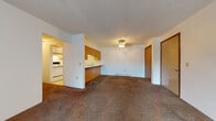 Located at 530 W Chicago St in Coldwater, Michigan, this single-floor unit offers a functional and straightforward layout designed for comfortable everyday living. The open living area is generously sized, featuring wall-to-wall carpet, a textured ceiling, a ceiling fan light fixture, and baseboard heating. A half-wall partition with warm wood-toned cabinetry separates the living space from a pass-through sink area, creating a natural transition into the kitchen. The galley-style kitchen is efficiently designed with white cabinetry accented by wood trim, ample upper and lower cabinet storage, a double sink, a full-size refrigerator, a dishwasher, and a range — all set atop easy-care vinyl tile flooring. The bedrooms are carpeted and bright, each benefiting from windows that bring in natural light and views of the surrounding greenery. One bedroom features a set of double sliding closet doors with warm wood detailing. The bathroom includes a wide vanity with under-sink cabinet storage, a large mirror, and vinyl tile flooring. Throughout the unit, wood-trimmed doors and warm-toned accents provide a cohesive, classic aesthetic.