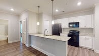 Located at 149 Sierra Vista Cir in Cornelia, Georgia, this single-floor residence offers a thoughtfully designed layout with modern finishes throughout. The open-concept kitchen and living area serves as the heart of the home, creating a seamless flow ideal for everyday living. The kitchen is well-appointed with white shaker-style cabinetry extending to the ceiling, light granite countertops, a large peninsula with an undermount stainless steel sink, and pendant lighting overhead. Black appliances, including a refrigerator, range, and over-the-range microwave, provide a striking contrast to the bright cabinetry. Crown molding accents the kitchen and living area, adding a refined architectural detail. Durable hardwood-style flooring runs throughout the main living spaces and bedrooms, offering a cohesive and easy-to-maintain surface. The bedrooms are generously sized, each featuring neutral-toned walls and windows with blinds that allow natural light to filter in. The bathroom includes a full tub and shower combination with built-in shelving. A dedicated laundry room with wire shelving and utility hookups adds everyday convenience. The overall ambiance is clean, neutral, and move-in ready, making this a functional and comfortable residence.