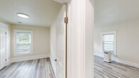 Located at 313 E St Joseph St in Lansing, Michigan, this 3-bedroom, 1-bathroom unit offers a clean, modern interior across a single floor. Light gray laminate flooring runs throughout the entire space, providing a cohesive and easy-to-maintain foundation in every room.

The spacious primary bedroom is the largest of the three, featuring multiple windows with blinds that allow ample natural light to fill the room. The two additional bedrooms are similarly bright, each with windows overlooking the outdoors and fresh, neutral wall tones that complement the light flooring.

The galley-style kitchen is well-appointed with white cabinetry on both sides, white appliances including a range and refrigerator, and light countertops. A window above the counter brings in natural light, making the kitchen feel open and functional.

The full bathroom includes a tub-shower combination, a white vanity with a sink, a large mirror, and matching light flooring, maintaining the clean aesthetic found throughout the unit.

A hallway connects the rooms efficiently, contributing to the straightforward and practical layout. Crisp white trim, panel-style doors, and softly painted walls lend the entire unit a fresh, well-maintained appearance throughout.