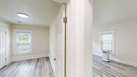 Located at 313 E St Joseph St in Lansing, Michigan, this 3-bedroom, 1-bathroom unit offers a clean, modern interior across a single floor. Light gray laminate flooring runs throughout the entire space, providing a cohesive and easy-to-maintain foundation in every room.

The spacious primary bedroom is the largest of the three, featuring multiple windows with blinds that allow ample natural light to fill the room. The two additional bedrooms are similarly bright, each with windows overlooking the outdoors and fresh, neutral wall tones that complement the light flooring.

The galley-style kitchen is well-appointed with white cabinetry on both sides, white appliances including a range and refrigerator, and light countertops. A window above the counter brings in natural light, making the kitchen feel open and functional.

The full bathroom includes a tub-shower combination, a white vanity with a sink, a large mirror, and matching light flooring, maintaining the clean aesthetic found throughout the unit.

A hallway connects the rooms efficiently, contributing to the straightforward and practical layout. Crisp white trim, panel-style doors, and softly painted walls lend the entire unit a fresh, well-maintained appearance throughout.