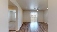 Located at 8855 N Casa Grande Hwy in Marana, Arizona, this single-story unit offers a well-designed layout with a cohesive blend of modern finishes and practical features throughout. The open living area is finished with rich wood-style plank flooring that extends through the main spaces, complemented by recessed lighting and a ceiling fan. Sliding glass doors dressed with vertical blinds invite natural light and provide access to an outdoor area with neighborhood views.

The kitchen is a standout feature, showcasing dark wood-tone cabinetry, light quartz countertops, a tile backsplash, black appliances including a range and microwave, pendant lighting, and a stainless steel sink. A dedicated in-unit laundry area is conveniently accessible from the main living space.

Bedrooms are carpeted for comfort, each equipped with ceiling fans and windows with blinds allowing natural light. The primary bedroom connects to a bathroom featuring a walk-in glass-door shower, while a second bathroom offers a full tub-shower combination. Both bathrooms include wood-style flooring and dark vanity cabinetry. The unit presents a clean, contemporary aesthetic throughout.