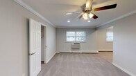 Located at Fairfield Country Club Gardens in East Islip, NY, this single-floor residence offers a thoughtfully designed layout with consistent finishes throughout. The living areas are finished with plush carpeting and painted in soft, neutral gray tones, creating a calm and cohesive atmosphere. Crown molding accents the ceilings throughout, adding a refined architectural detail to each room. Ceiling fans with integrated lighting fixtures are present in the main living and bedroom spaces, contributing to both comfort and style.

The kitchen is outfitted with rich, warm-toned wood cabinetry featuring raised-panel doors, dark granite countertops, a tiled backsplash, and stainless steel appliances including a range, microwave, and dishwasher. The bedrooms are generously proportioned, each featuring carpeted floors, crown molding, ceiling fans with recessed lighting, and closet access. Natural light filters in through windows, offering views of the surrounding neighborhood.

The bathroom includes a tub and shower combination enclosed by sliding glass doors, with clean white tile work accented by diamond-pattern tile details. A carpeted staircase with a warm wood handrail provides access between levels. The overall design is clean, functional, and move-in ready.