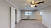 Located at Fairfield Country Club Gardens in East Islip, NY, this single-floor residence offers a thoughtfully designed layout with consistent finishes throughout. The living areas are finished with plush carpeting and painted in soft, neutral gray tones, creating a calm and cohesive atmosphere. Crown molding accents the ceilings throughout, adding a refined architectural detail to each room. Ceiling fans with integrated lighting fixtures are present in the main living and bedroom spaces, contributing to both comfort and style.

The kitchen is outfitted with rich, warm-toned wood cabinetry featuring raised-panel doors, dark granite countertops, a tiled backsplash, and stainless steel appliances including a range, microwave, and dishwasher. The bedrooms are generously proportioned, each featuring carpeted floors, crown molding, ceiling fans with recessed lighting, and closet access. Natural light filters in through windows, offering views of the surrounding neighborhood.

The bathroom includes a tub and shower combination enclosed by sliding glass doors, with clean white tile work accented by diamond-pattern tile details. A carpeted staircase with a warm wood handrail provides access between levels. The overall design is clean, functional, and move-in ready.