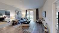 This single-floor residence at Northwest Parkway in Elgin, Illinois, presents a contemporary design with a neutral color palette and modern finishes throughout. The open-concept living area is anchored by wood-look plank flooring and features a sliding glass door that opens to an outdoor patio, allowing natural light to fill the space and providing views of the surrounding community.

The kitchen is outfitted with tall white shaker-style cabinetry, stainless steel appliances including a gas range, microwave, and refrigerator, complemented by light quartz countertops and pendant lighting. A kitchen island or peninsula provides additional prep and seating space.

The bedrooms are carpeted for comfort and each includes large windows that frame outdoor views, offering a calm and well-lit retreat. Closet access is conveniently positioned in each room.

The bathrooms feature clean, modern finishes. One bathroom includes a dual-sink vanity with a white quartz countertop and ample storage, while another offers a glass-enclosed walk-in shower with tile surround and wood-look flooring, maintaining the contemporary aesthetic found throughout the unit.

Overall, the space delivers a cohesive, well-designed interior suited for comfortable everyday living.