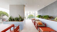 Located at 501 Broadway in Santa Monica, California, this generously sized balcony offers a well-appointed outdoor living experience in the heart of one of LA's most sought-after neighborhoods. The space features a clean, contemporary design with large-format porcelain tile flooring and a crisp white overhead canopy that provides shade while maintaining an open, airy feel.

A full-length glass railing runs along the perimeter, ensuring unobstructed views of the bustling Broadway streetscape below, the surrounding modern architecture, and the lush tree-lined sidewalks of Santa Monica. The transparency of the glass barriers enhances the sense of openness and seamlessly connects the interior to the urban environment outside.

A striking slate-gray accent wall serves as the backdrop for a raised planter box overflowing with vibrant greenery, adding a natural, garden-like element to the space. Bold orange outdoor furniture — including lounge chairs, a coffee table, and a dining set — creates a lively contrast against the neutral tones of the floor and walls, lending the balcony a warm, inviting character.

The layout is thoughtfully organized to accommodate both dining and relaxed lounging, making it a versatile outdoor retreat. Its elevated position provides commanding views of the dynamic Santa Monica streetscape and the contemporary mixed-use buildings that define this vibrant urban corridor.
