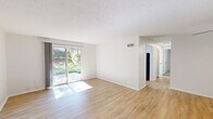 Located at 10301 Briar Hollow Dr in Saint Louis, MO, this single-floor, three-bedroom, one-bathroom residence offers a clean and functional layout throughout. The living room is a standout space, featuring light hardwood-style flooring, a textured ceiling, and a full-width sliding glass door that floods the room with natural light and opens to a private outdoor patio with lush greenery views. The kitchen is well-appointed with white cabinetry, stainless steel appliances including a gas range and refrigerator, light countertops, and a window that brings in additional natural light. The three bedrooms are carpeted for comfort, with each room offering windows that allow ample daylight. The spacious primary bedroom includes a built-in closet with shelving. A ceiling fan is featured in one of the secondary bedrooms. The full bathroom includes a tub-shower combination with clean white surround and chrome fixtures. A dedicated hallway connects all rooms efficiently, and a closet provides additional storage. The overall aesthetic is bright, neutral, and move-in ready, with consistent white walls and light finishes throughout that lend a fresh and airy ambiance to the entire space.