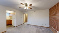This single-floor unit offers a well-organized layout with a variety of functional living spaces. The main living area is finished with plush carpeting and features a ceiling fan with light fixture, providing both comfort and air circulation. Adjacent to the living space is a dedicated entryway with durable wood-look flooring, a solid entry door, and a window that lets in natural light.

The kitchen is equipped with warm oak cabinetry, a white electric range, and matching wood-look flooring that ties the space together cohesively. A full bathroom includes a single-sink vanity with oak cabinetry, a toilet, and a tub-shower combination with a white surround, all set on wood-look flooring.

The bedrooms are carpeted and well-lit, with multiple windows providing natural light. A standout feature throughout the sleeping quarters is the exposed red brick accent wall, adding character and a rustic charm to the space. One bedroom includes a walk-in closet with a hanging rod, offering generous storage. Textured ceilings are present throughout much of the unit.

Overall, the space presents a clean, functional design with consistent warm-toned wood trim, neutral wall colors, and a comfortable mix of carpet and hard-surface flooring across its rooms.