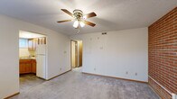 This single-floor unit offers a well-organized layout with a variety of functional living spaces. The main living area is finished with plush carpeting and features a ceiling fan with light fixture, providing both comfort and air circulation. Adjacent to the living space is a dedicated entryway with durable wood-look flooring, a solid entry door, and a window that lets in natural light.

The kitchen is equipped with warm oak cabinetry, a white electric range, and matching wood-look flooring that ties the space together cohesively. A full bathroom includes a single-sink vanity with oak cabinetry, a toilet, and a tub-shower combination with a white surround, all set on wood-look flooring.

The bedrooms are carpeted and well-lit, with multiple windows providing natural light. A standout feature throughout the sleeping quarters is the exposed red brick accent wall, adding character and a rustic charm to the space. One bedroom includes a walk-in closet with a hanging rod, offering generous storage. Textured ceilings are present throughout much of the unit.

Overall, the space presents a clean, functional design with consistent warm-toned wood trim, neutral wall colors, and a comfortable mix of carpet and hard-surface flooring across its rooms.