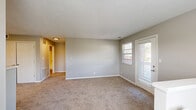 Located at 834 S Sheridan Drive in Muskegon, MI, this two-story, 1-bedroom, 1-bathroom home offers a thoughtfully organized layout spread across two levels. The entry level provides staircase access to the main living floor above, which houses the majority of the home's living space. The combined kitchen and living room area forms the heart of the home, featuring light hardwood-style flooring, white cabinetry with modern hardware, light countertops, and stainless and black appliances including a refrigerator, electric range, and dishwasher. An in-unit washer and dryer are also conveniently located within the kitchen area. Multiple windows allow natural light to brighten the open living space, which features neutral gray walls, plush carpeting, and a textured ceiling. The spacious bedroom is carpeted and bathed in natural light from a large window, and includes direct access to a dedicated walk-in closet with built-in shelving and hanging rods. The full bathroom is finished with wood-look flooring, a white vanity with clean countertops, and a full tub-shower combination with a curved curtain rod. Neutral gray tones throughout the home create a cohesive, move-in-ready aesthetic.