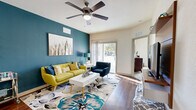 Located at 250 Cherry Ridge Dr in Jacksonville, FL, this single-story, 2-bedroom, 2-bathroom residence offers a thoughtfully designed layout across a comfortable footprint. Rich hardwood-style flooring flows through the main living areas, complemented by a striking teal accent wall that anchors the bright, open living room. A ceiling fan overhead and sliding glass doors leading to a private balcony enhance the airy atmosphere, filling the space with natural light and outdoor views.

The kitchen is outfitted with dark cabinetry, stainless steel appliances, and a peninsula with bar seating, making it ideal for both everyday cooking and casual entertaining. Pendant lighting adds a modern touch to the space.

The primary bedroom is generously sized, featuring plush carpet, a ceiling fan, and ample natural light from large windows. It is complemented by a spacious walk-in closet with built-in wire shelving for organized storage. The second bedroom offers a cozy, well-lit retreat with its own distinct character.

Both bathrooms feature dark vanity cabinetry, countertop sinks, hardwood-style flooring, and a shower-tub combination. A dedicated laundry area and hallway with closet storage round out this efficiently organized home, delivering practical comfort throughout.
