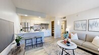 Located at 520 W Prince Rd in Tucson, Arizona, this one-bedroom, one-bathroom unit offers a well-designed, single-floor layout that maximizes every square foot of living space. Wood-look plank flooring runs throughout, providing a cohesive and contemporary aesthetic.

The open-concept living area is bright and welcoming, featuring a large window that draws in natural light and provides views of the surrounding outdoors. The space flows seamlessly into the kitchen, which is outfitted with white cabinetry, a gray subway tile backsplash, stainless steel appliances including a refrigerator and range, and a breakfast bar with seating — ideal for casual dining. An adjacent open shelving nook offers additional storage and display space.

The bedroom is a comfortable, well-proportioned retreat featuring a window with natural light, textured ceiling, and wood-look flooring. A wall-mounted sconce adds a refined touch near the hallway entry.

The bathroom is clean and functional, finished with wood-look tile flooring, a white vanity with ample counter space, and a full tub and shower combination with a curtain enclosure. Neutral wall tones and framed artwork contribute to a calm, polished atmosphere.

Throughout the unit, a consistent neutral color palette, textured ceilings, and modern finishes create a cohesive and move-in ready living environment.
