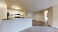 Located at 4880 50th St W in Bradenton, Florida, this single-story unit offers a practical and functional layout with a clean, neutral aesthetic throughout. The open-concept design connects the kitchen and living areas seamlessly, creating a spacious and versatile environment well-suited for everyday living.

The kitchen is well-appointed with white cabinetry offering generous storage, dark countertops, and a full suite of black appliances including an electric range, refrigerator, and dishwasher. Wood-look flooring runs through the kitchen and dining areas, providing a durable and attractive surface, while plush carpet extends through the living room and bedroom areas for added comfort.

The living room is generously sized, featuring a sliding glass door that opens to a private balcony, allowing natural light to filter in and offering views of the surrounding greenery. The neutral wall tones and textured ceilings are consistent throughout the unit, creating a cohesive and understated atmosphere.

The bathroom is well-designed with a wide vanity featuring white cabinetry, a large mirror, and a soaking tub with tiled surroundings. A window allows natural light into the space. Throughout the unit, white trim and blinds on windows contribute to a tidy, uniform appearance.